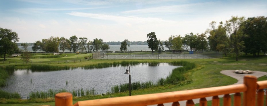 View of the lake from a deck with a tennis court in the background