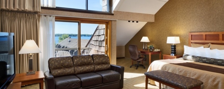 Window with a lake view, sofa, king bed, desk with chair