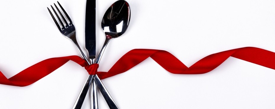 A fork, a knife, and a spoon neatly tied with a red ribbon.