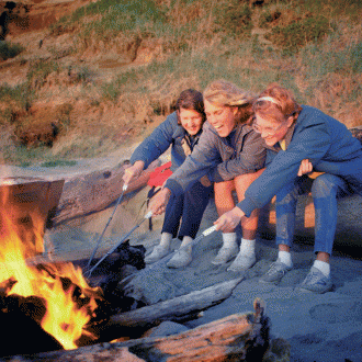 3 women roasting food in the bonfire