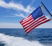 An american flag flows in the wind over a lake